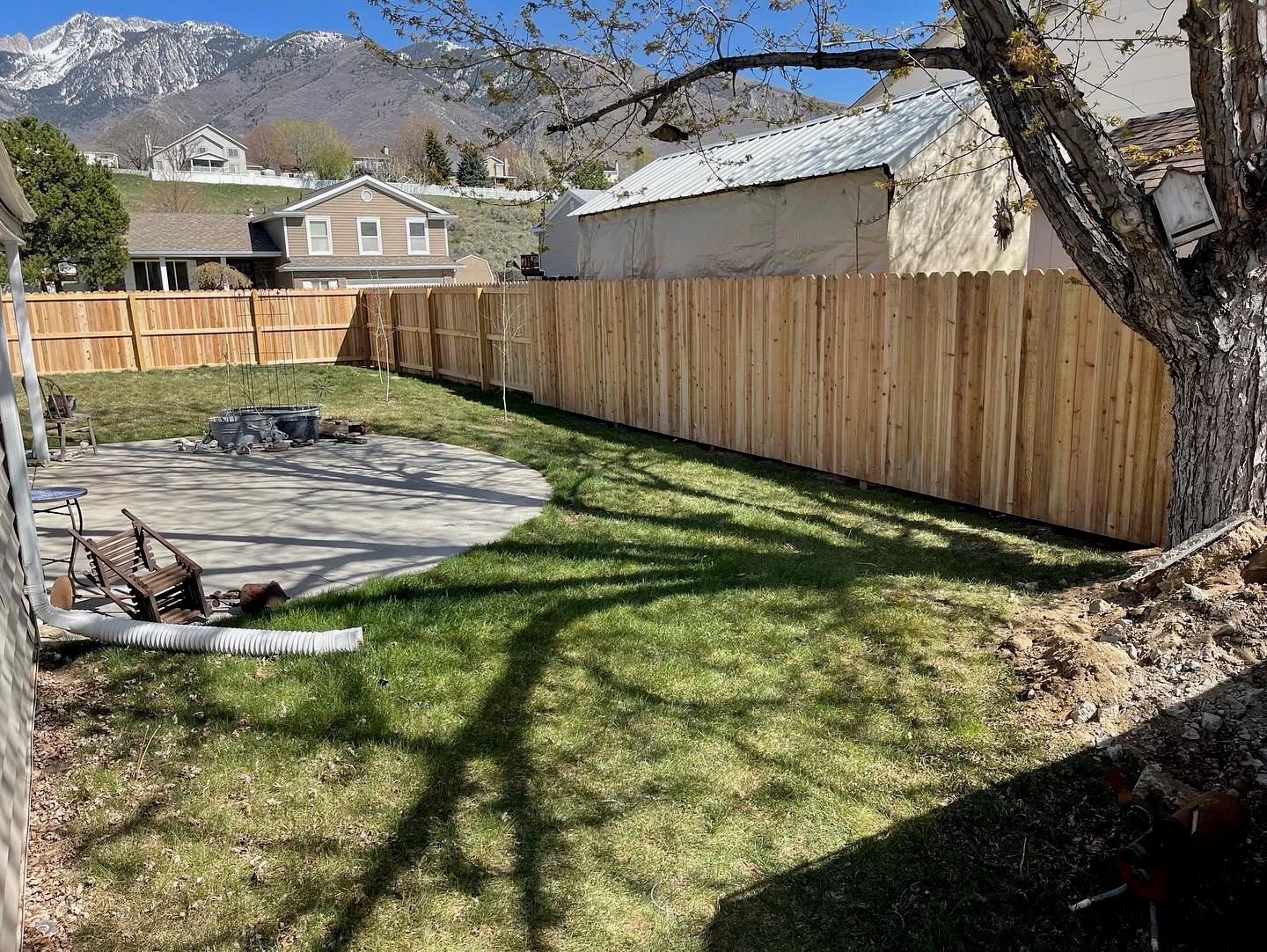 New cedar privacy fence framing a green Utah backyard beneath the mountains