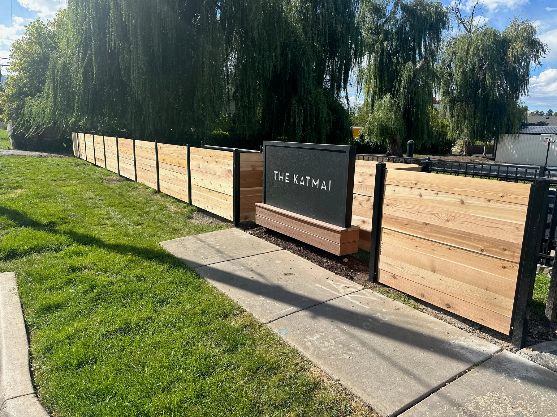 Cedar and black steel commercial entry gate beside a landscaped Utah property