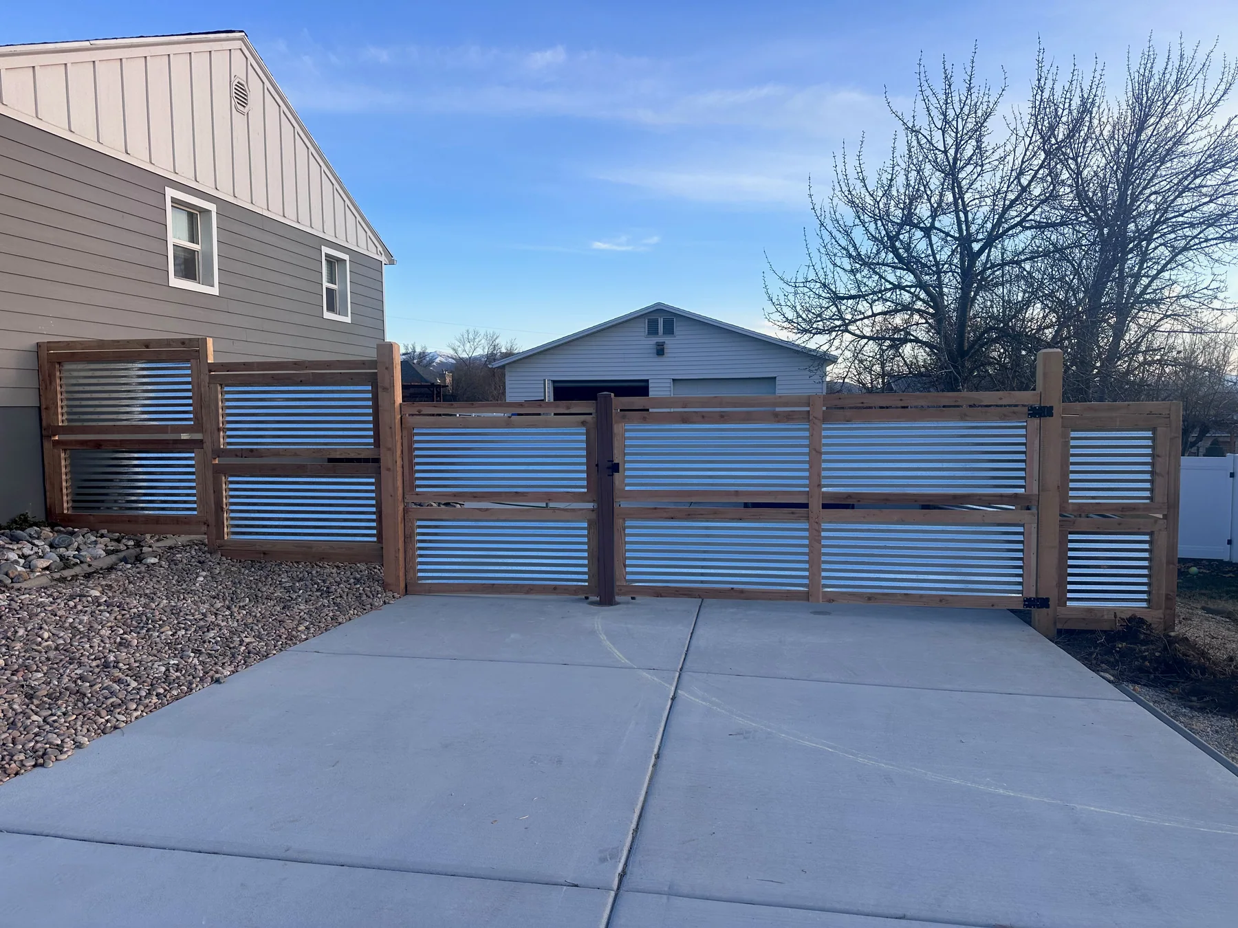 Custom corrugated metal driveway gate with warm wood framing at a Utah home