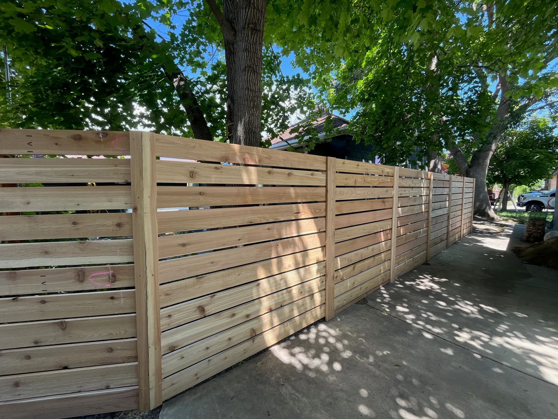 Horizontal cedar privacy fence following a shaded Utah side yard