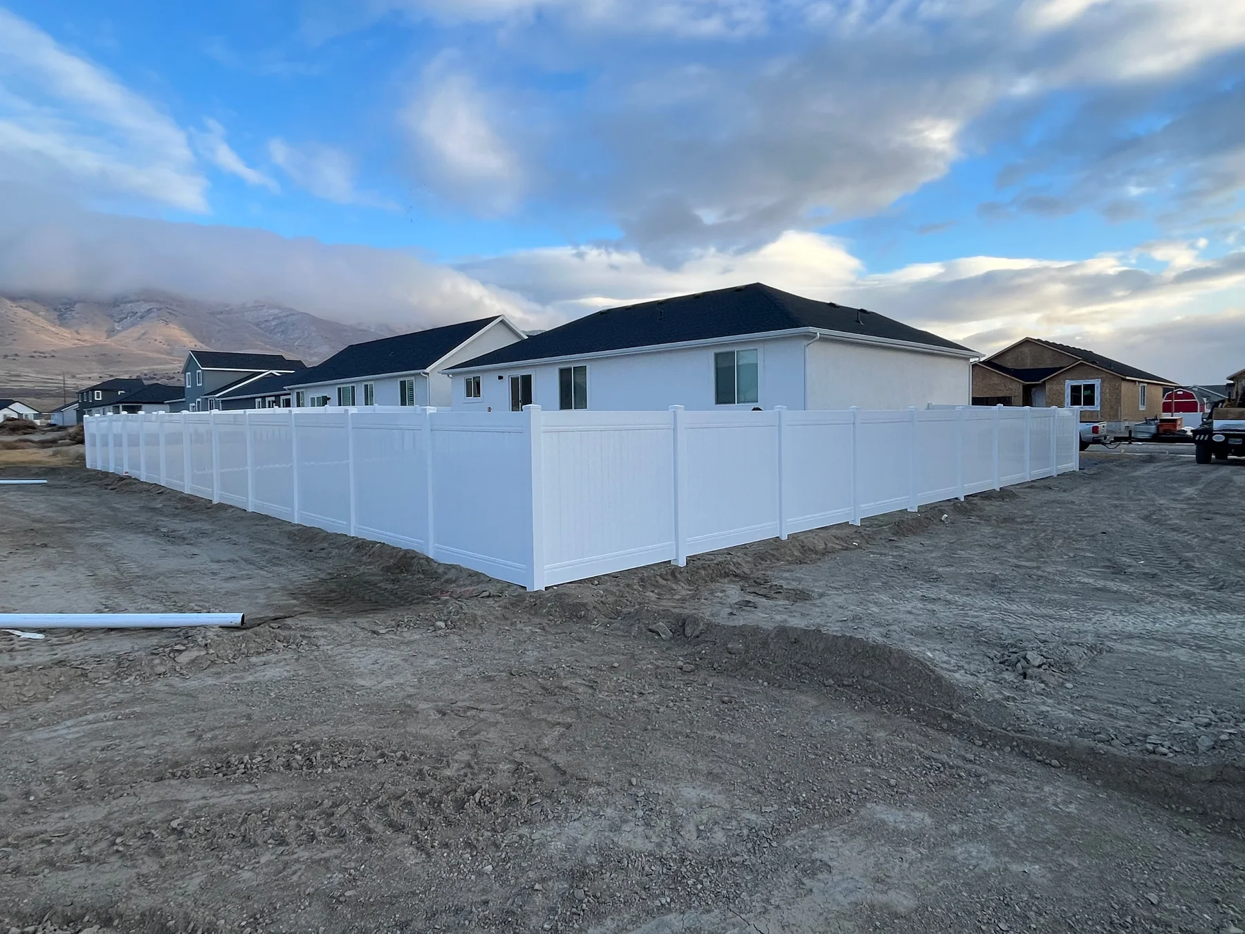 White vinyl privacy fence wrapping a new Utah home with mountains behind it