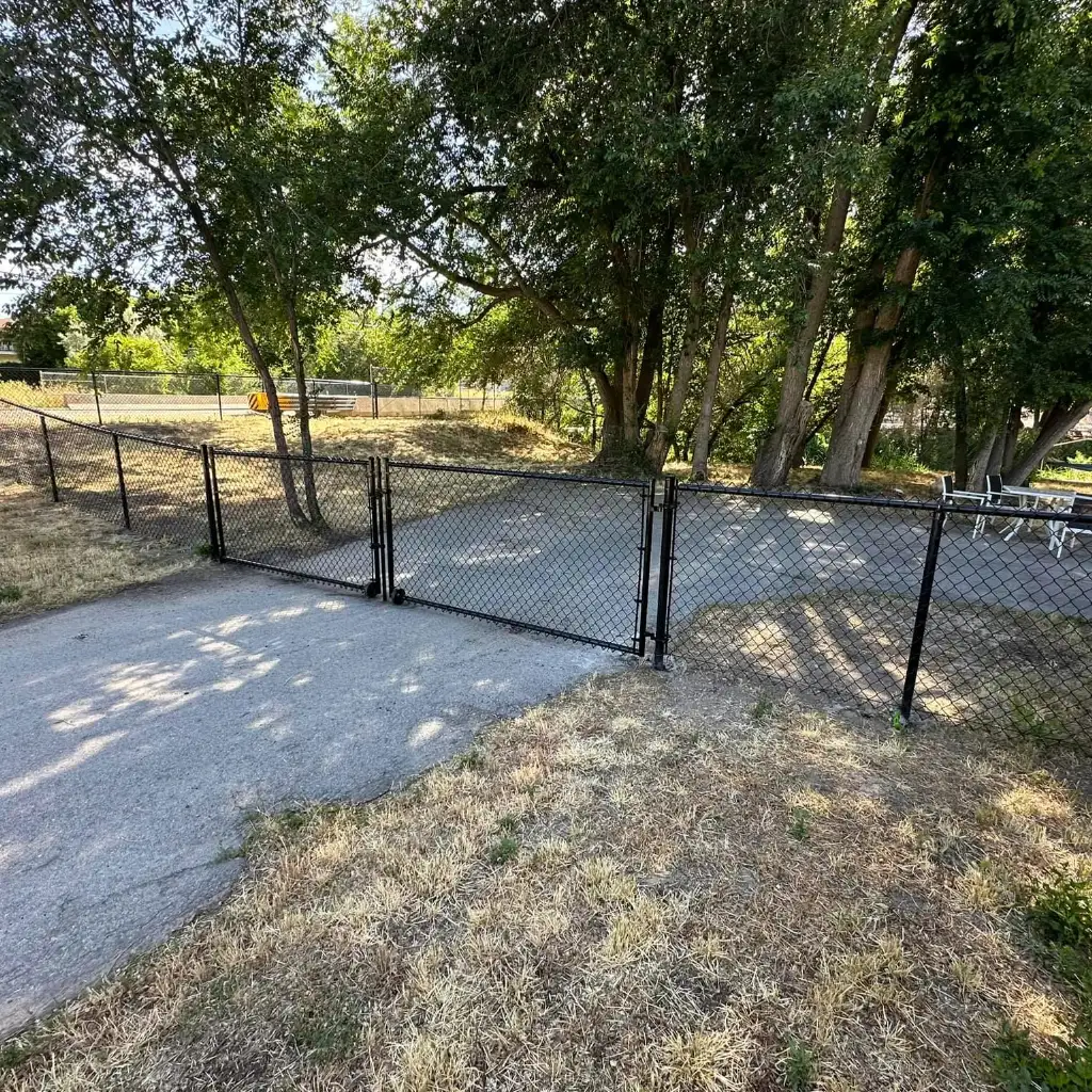 Black chain-link sport court enclosure with Utah mountains behind it