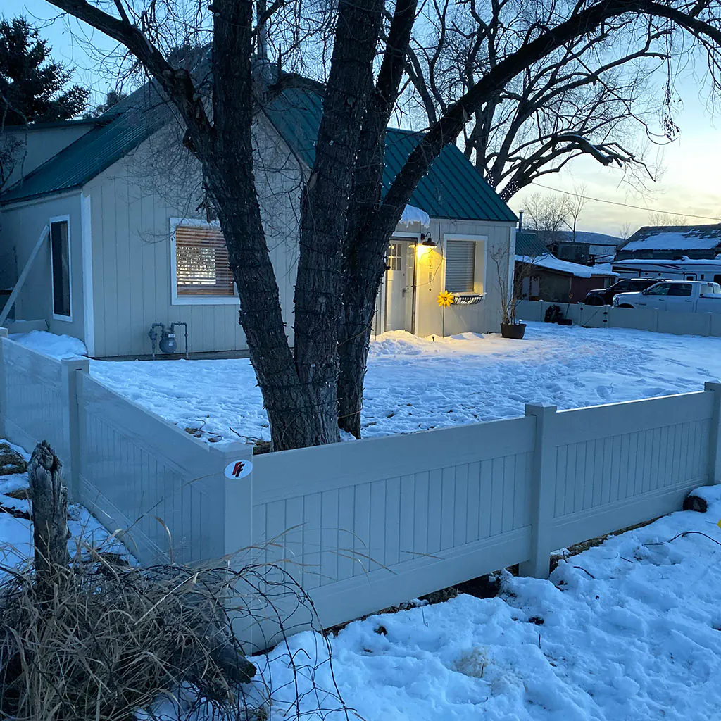 White vinyl privacy fence installed around a Utah home in winter